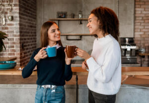 Duas amigas sorrindo e tomando café, ilustrando a resistência à pigmentação das facetas em resina na Clínica Lima Odonto em Bauru.