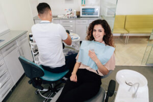 Mulher sorridente com cabelos cacheados na cadeira odontológica para um check-up no dentista na Clínica Lima Odontologia em Bauru.