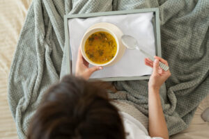 Mulher segurando bandeja com sopa, ilustrando a dieta macia ideal para a adaptação da alimentação após implante dentário em Bauru.